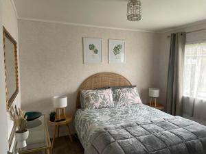 a bedroom with a bed and two tables with lamps at POHUTUKAWA PLACE in Matamata