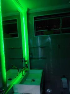 Baño verde con lavabo y espejo en Super aconchegante Bem localizado, prox Ibirapuera, en São Paulo