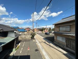 een raam met uitzicht op een straat met huizen bij machiyado Kuwanajuku Edomachi 21 in Kuwana