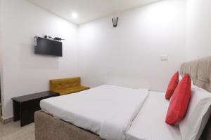 Hotel Metro Regency في لاكناو: غرفة نوم بسرير وأريكة مع وسائد حمراء