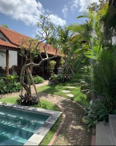 a garden with a swimming pool next to a house at Jinar Guest House in Canggu