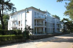 ein weißes Gebäude mit Straßenbeleuchtung davor in der Unterkunft Ostseeresidenz Gorki- Park - 23 mit Wellness und Schwimmbad in Bansin