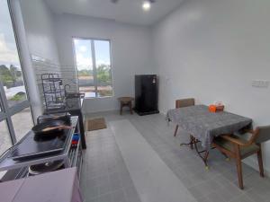a living room with a table and a kitchen with a stove at Lembah Saerah Resort in Kangar
