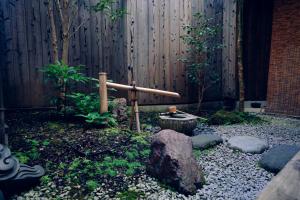a garden with a bamboo wand in front of a fence at Kotone Machiya-Inn 京町家旅宿 小都音 in Kyoto