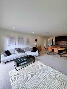 Luxury 3 Bedroom Home With Double Garage في كرايستشيرش: غرفة معيشة مع أريكة بيضاء وطاولة
