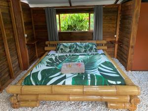 drewnianym łóżkiem w pokoju z oknem w obiekcie Fare Tahima w Fare
