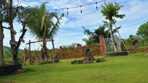 einen Garten mit einem Zaun, Bäumen und einem Grasfeld in der Unterkunft Sunny Eco Lodge in Cat Tien