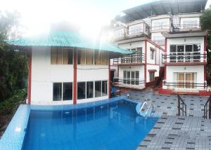 ein Hotel mit einem Pool vor einem Gebäude in der Unterkunft Green Trees Munnar in Munnar