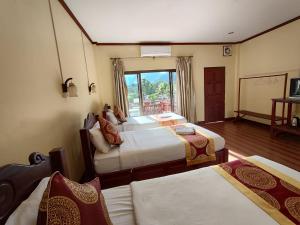 a hotel room with two beds and a window at Hana Riverside Hotel in Vang Vieng