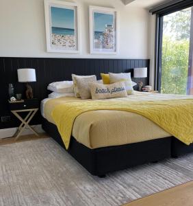 a bedroom with a large bed with a yellow blanket at Hyams Beach House A - Brand new lux beach Oasis in Hyams Beach