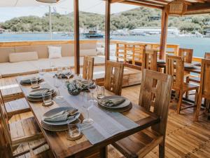 una mesa de madera con platos y copas de vino en un barco en Labuan Bajo Trip, en Nggorang