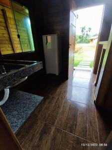 a bathroom with a door open to a hallway with wood floors at Chalés Maravilha 04 in Alfredo Chaves