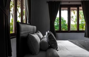 um quarto com uma cama com almofadas e janelas em Anahata Resort em Lipa Noi