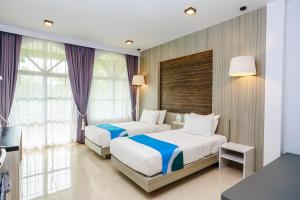 a hotel room with two beds and a desk and window at Ao Nang Baan Suan Resort in Ao Nang Beach +33 photos