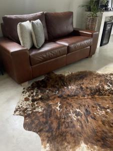 un sofá de cuero marrón sentado en una sala de estar con una alfombra en Market on 5, en Piet Retief