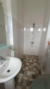 La salle de bains blanche est pourvue d'un lavabo et d'une douche. dans l'établissement Smile Hub Kandy Penthouse apartment, à Kandy