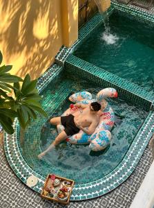 two people riding on inflatables in a swimming pool at Alsahar Hoi An Boutique Villa in Hoi An