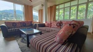 sala de estar con sofás, mesa y ventanas en Smile Hub Kandy Penthouse apartment, en Kandy