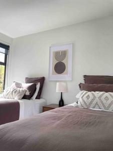 a bedroom with two beds and a table with a lamp at Luxury 3 Bedroom Home With Double Garage in Christchurch +51 photos