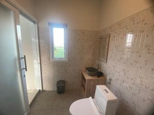 a bathroom with a white toilet and a window at D'A HOUSE in Amed