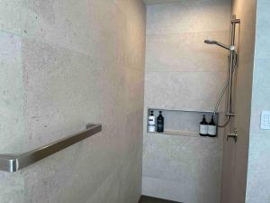 a bathroom with a shower with bottles on a wall at Luxury 3 Bedroom Home With Double Garage in Christchurch