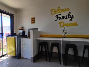 uma cozinha com um bar com bancos e um cartaz que lê acredita no sonho da família em Stylish Colourfull Getaway em Margaret River