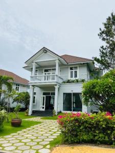 a white house with flowers in the front yard at Family Villa in Sea Links Beach City Mũi Né in Mui Ne