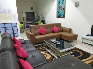 LILY VACATION HOME at CAMERON HIGHLANDS - 12 PAX,FREE WiFi w CARPORCH في تاناه راتا: غرفة معيشة مع أريكة بنية ومخدات وردية