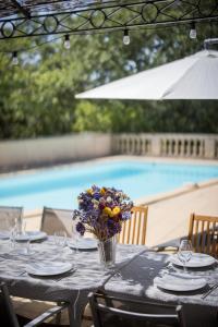 a table with a vase of flowers on it next to a pool at Le Mas de la Catounière in Castillon-du-Gard