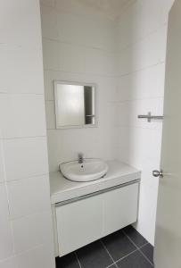 a white bathroom with a sink and a mirror at G Residence - 2BR Family Suite Barrington Night Market - 3 in Brinchang