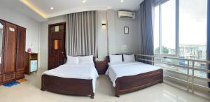 two beds in a room with a balcony at Thanh Thu 1 Hotel in Kon Tum (2)