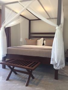 a bedroom with a canopy bed and a wooden bench at Waters Edge Liwonde in Liwonde