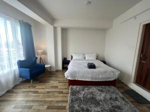 um quarto de hotel com uma cama e uma cadeira azul em Mulberry Inn BnB em Shillong