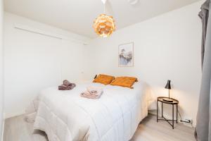 ein weißes Schlafzimmer mit einem weißen Bett und orangefarbenen Kissen in der Unterkunft Nordic Wooden House in Rovaniemi