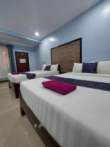 a bedroom with three beds and a wall at Nika's House in Siem Reap