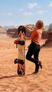 a woman holding a skateboard in the desert at Full moon camp in Disah