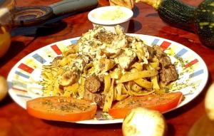 um prato de comida com carne e massas numa mesa em Glamping Cabaña el Porvenir 10601 em Manta