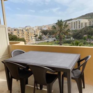 una mesa y sillas en un balcón con vistas en Gozo Belle Mare Apartments, en Marsalforn