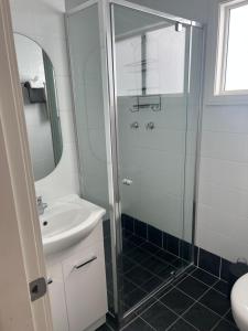 a bathroom with a shower and a sink at Batemans Bay North Bush Cottages in Benandarah