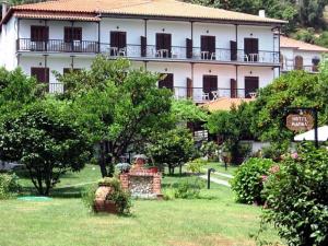 ein großes weißes Gebäude in einem Park mit Bäumen in der Unterkunft Hotel Marina in Agios Ioannis