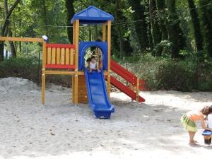 ein Kind spielt auf einem Spielplatz im Sand in der Unterkunft Hotel Marina in Agios Ioannis