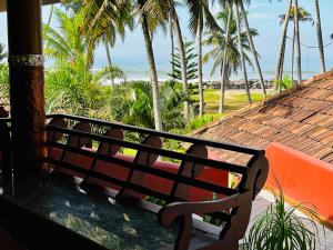 a bench sitting on a porch looking at the beach at Maadathil Cottages & Beach Resort in Varkala