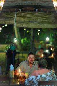 Ein Mann und eine Frau sitzen an einem Tisch in der Unterkunft Maadathil Cottages & Beach Resort in Varkala