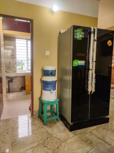 a large refrigerator in a room with a green stool at Asma-ul-husna apartment in Rājshāhi