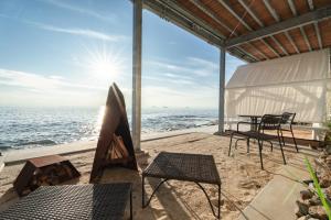 a patio with chairs and a table on the beach at Glamping＆Resort WOOD DESIGN PARK NOMA in Noma