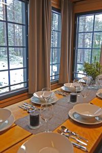 une table avec des assiettes et des verres sur une table avec des fenêtres dans l'établissement Tunturipöllö 1, à Ruka