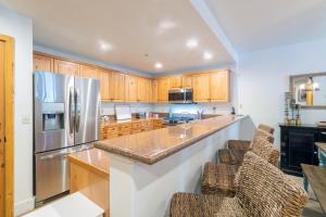 a kitchen with wooden cabinets and a stainless steel refrigerator at Bear Creek Lodge 111A by Alpine Lodging Telluride in Telluride