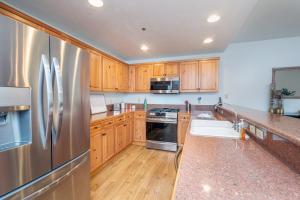 a kitchen with wooden cabinets and a stainless steel refrigerator at Bear Creek Lodge 111A by Alpine Lodging Telluride in Telluride