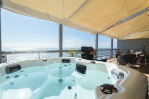 a jacuzzi tub with a view of the ocean at Glamping＆Resort WOOD DESIGN PARK NOMA in Noma
