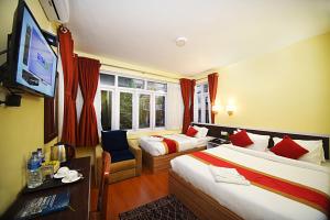una camera d'albergo con due letti e una TV a schermo piatto di Hotel Odyssey Nepal a Kathmandu